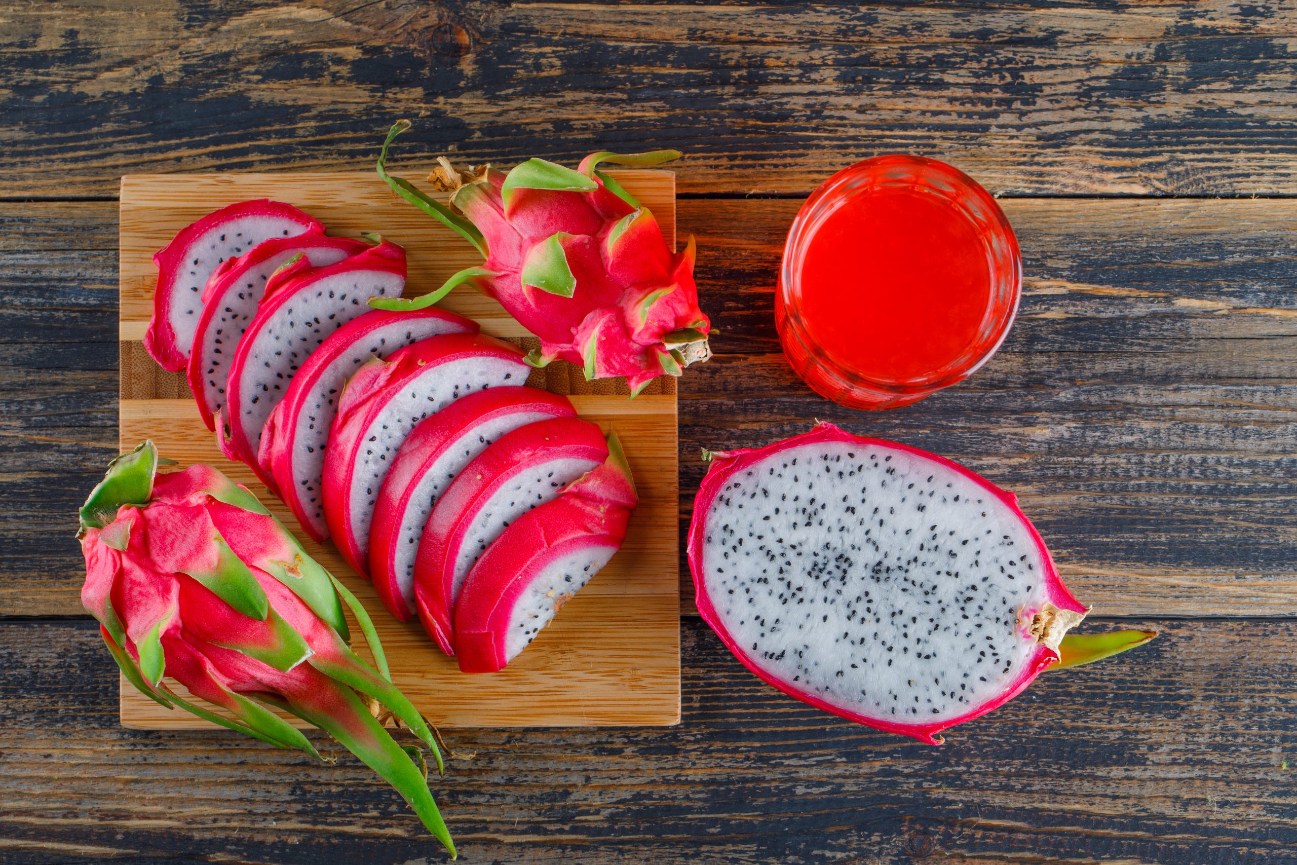 Dragon fruit with juice flat lay on wooden and cutting board background