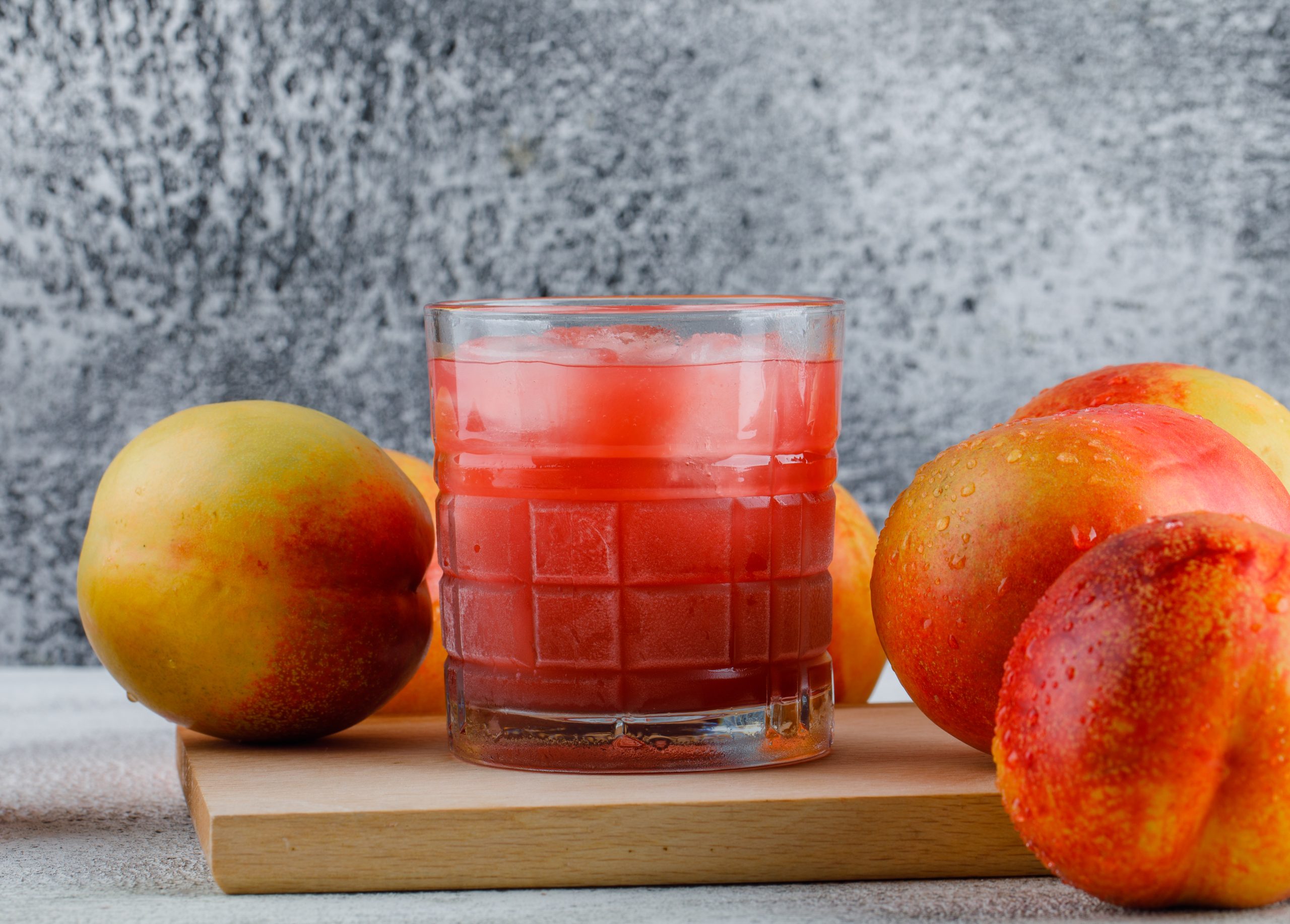 Nectarines with juice on grungy and cutting board background, side view